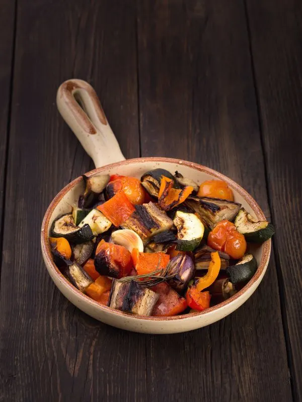 spanish roasted vegetables in a pot on a wooden table.