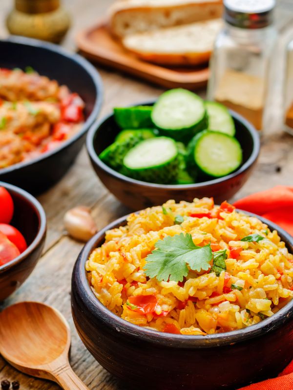 spanish saffron rice in a black bowl with other vegetables in the background. - Flavorful Spanish Saffron Rice Recipe