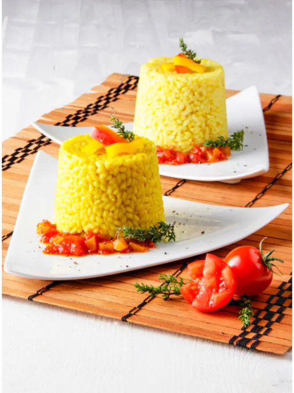 spanish saffron rice served on 2 plates with tomatoes.