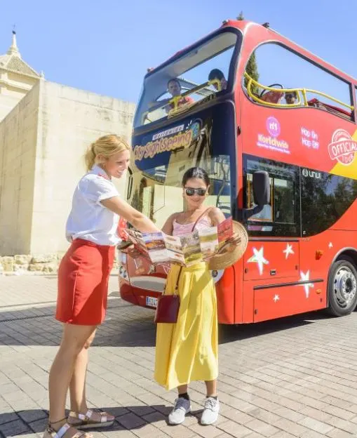 2 women standing in front of a hop-on hop-off bus in Seville, Spain