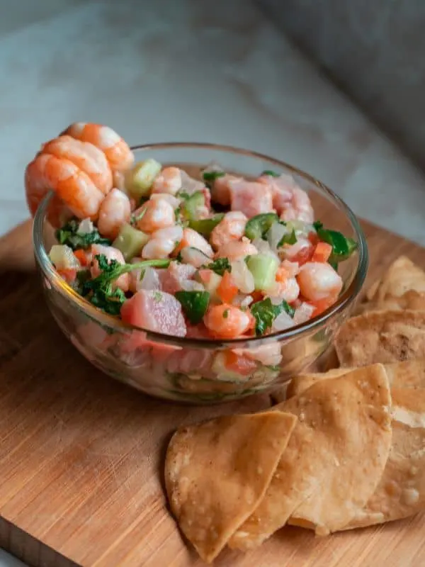 Spanish ceviche recipe with shrimp served on a wooden board with tortilla.