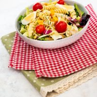 a bowl of spanish macaroni pasta with egg, tomatoes and veggies on kitchen tablecloths