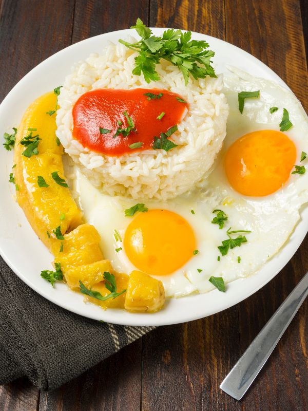 arroz a la cubana, rice with eggs and bananas on a white plate. Easy Spanish Arroz a la Cubana Recipe