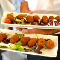 chef holding 2 plates of Spanish croquettes, Marbella in May