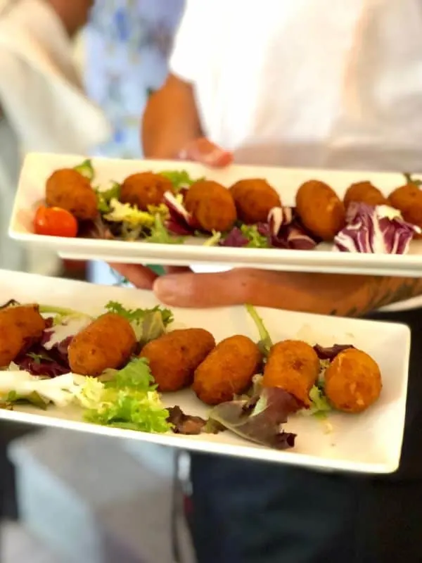 chef holding 2 plates of Spanish croquettes, Marbella in May