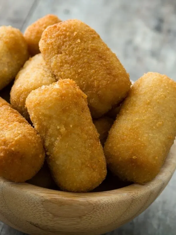 spanish croquettes recipe on a black plate, on a wooden table.