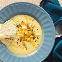 gazpacho recipe with corn in a blue bowl served with flat bread.