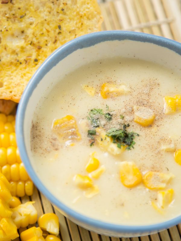 corn gazpacho with corn and seasoning on top serve din a soup bowl.