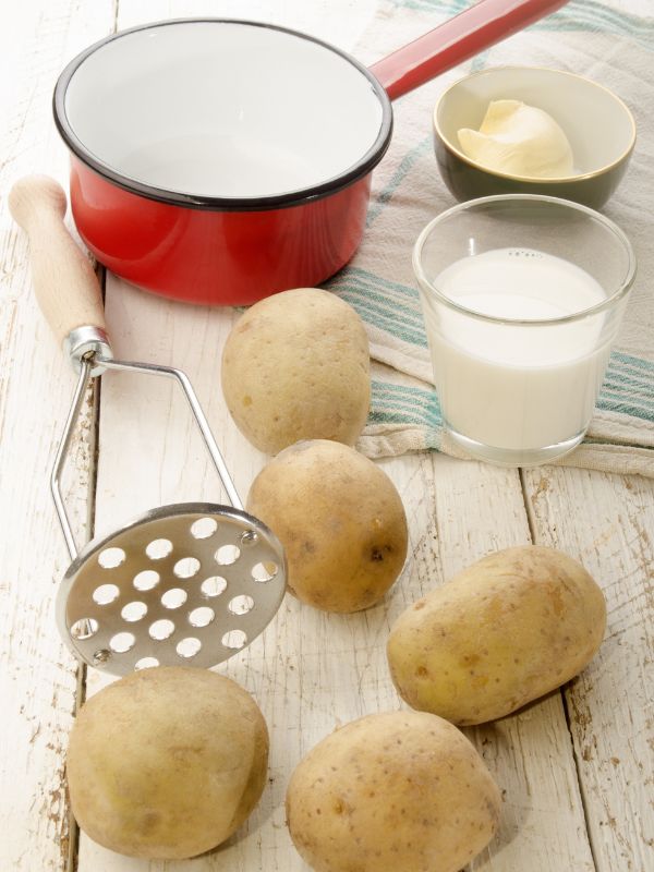 ingredients for spanish mashed potatoes like potatoes, cream, butter on a wooden table