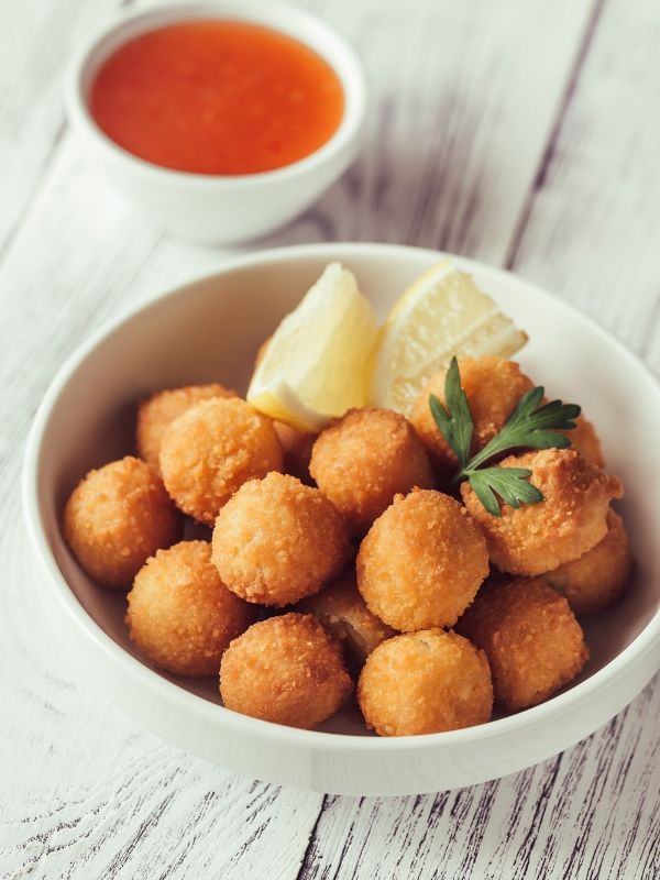 shrimp croquettes in a withe bowl, served with lemon and sauce.