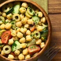 spanish chickpea salad in a wooden bowl next to a fork