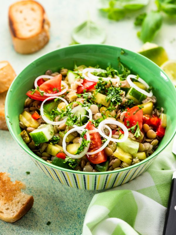 spanish lentil salad in a green bowl with toast next to it. Healthy Spanish Lentil Salad Recipe