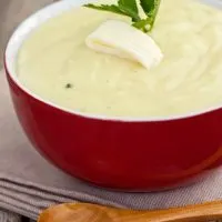 spanish mashed potatoes in a red bowl with butter and parsley on top