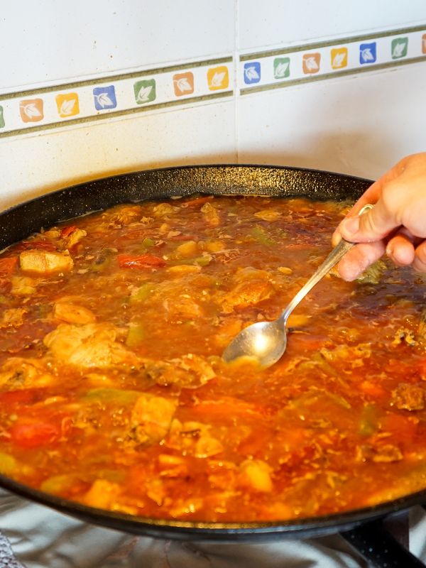 valencian paella recipe being made in a pan on the stove.