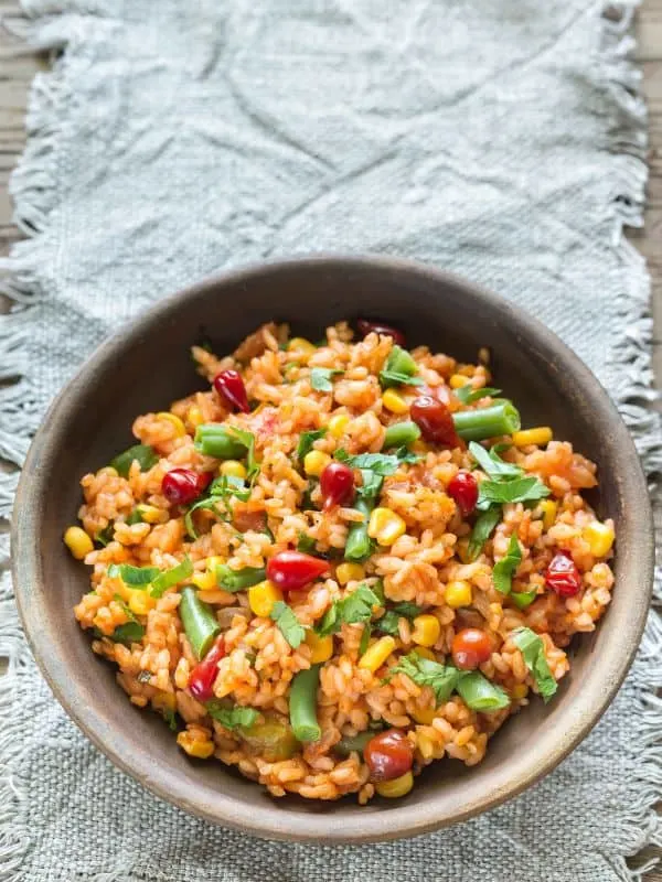 Spanish rice with corn in a clay bowl - Quick Spanish Rice with Corn Recipe