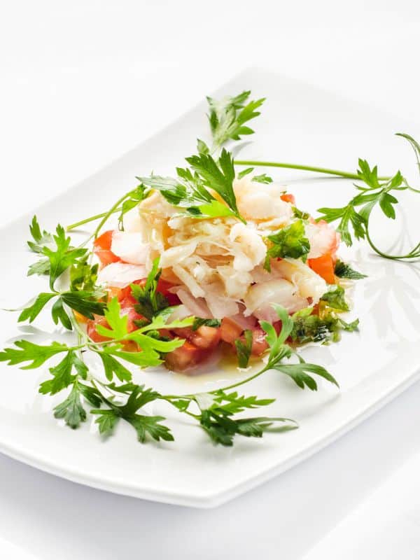 ensalada de bacalao served on a white plate with fresh parsley.