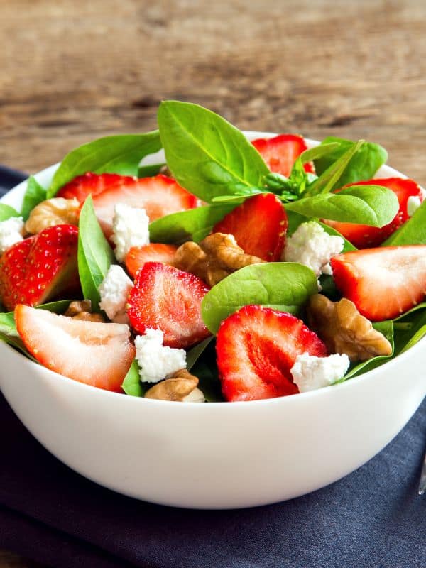 ensalada de espinacas, spanish spinach salad with strawberry and walnuts in a white bowl