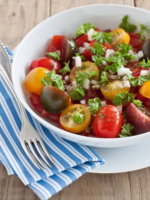 spanish tomato salad with cherry tomatoes and onion in a white bowl.