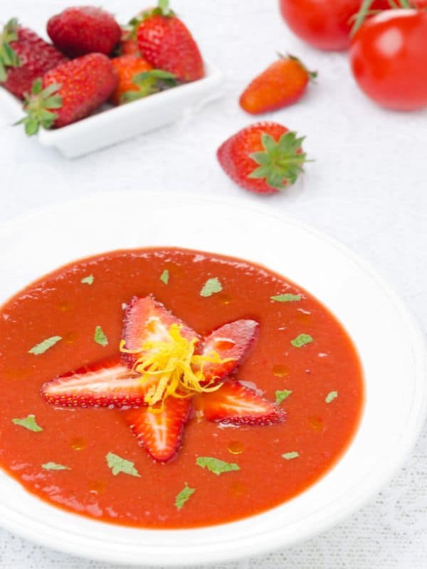 strawberry gazpacho in a bowl with strawberries on top. 