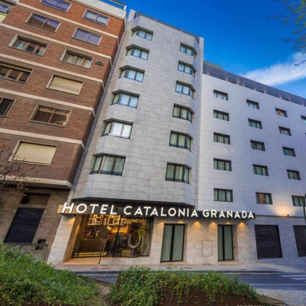 a facade of hotel catalonia in granada, spain with a glass door and windows