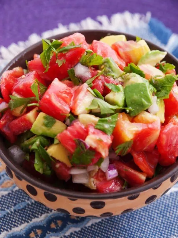 a closeup of with a bowl of ensalada de aguacatespanish avocado salad with tomatoes - Easy Ensalada de Aguacate Recipe [Spanish Avocado Salad]