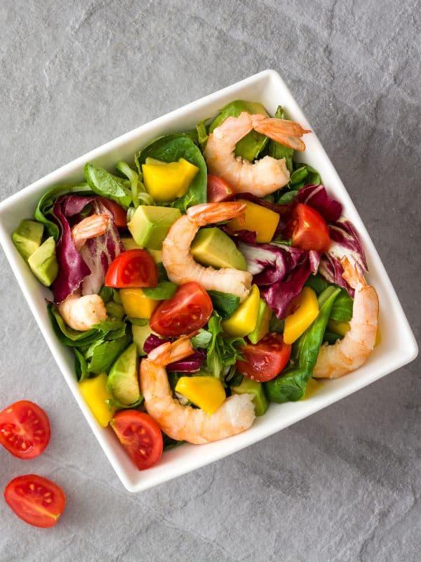 ensalada de aguacate, spanish avocado salad with tomatoes and shrimp in a bowl