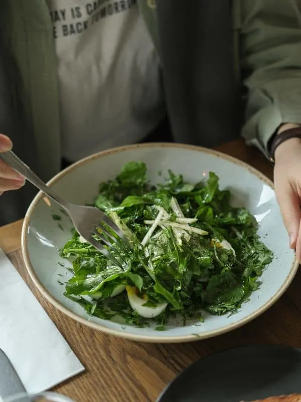 man eating a Spanish green salad from a bowl.