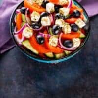spanish summer salad with tomatoes, olives, onion and feta in a bowl