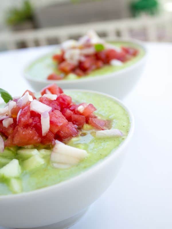 zucchini gazpacho in 2 bowls with fresh tomato on top