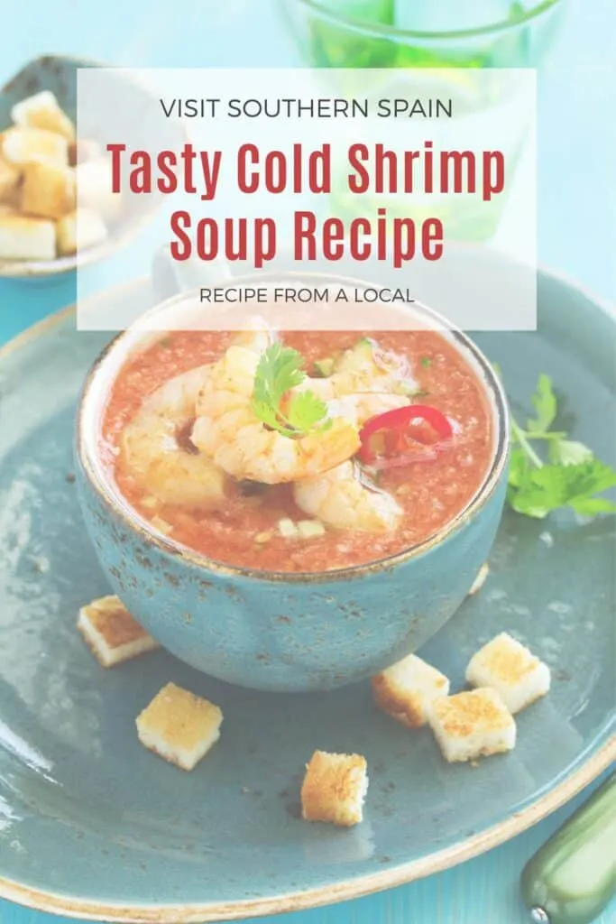 a pin with a blue bowl of cold shrimp soup served with crutons.