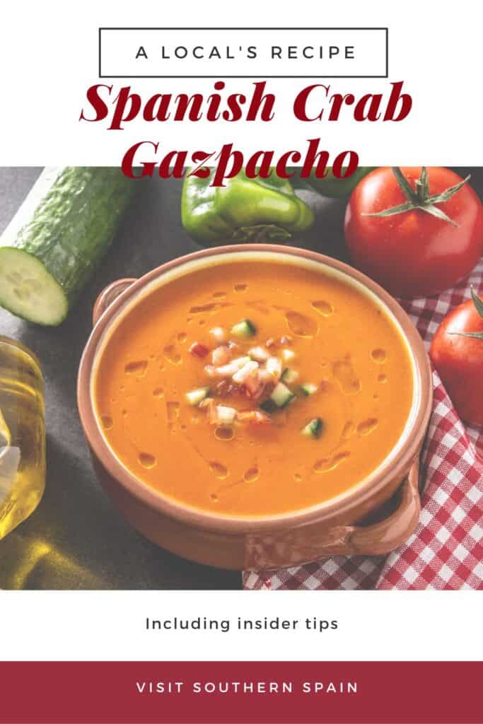 a pin with a clay bowl of crab gazpacho with fresh vegetables around it.