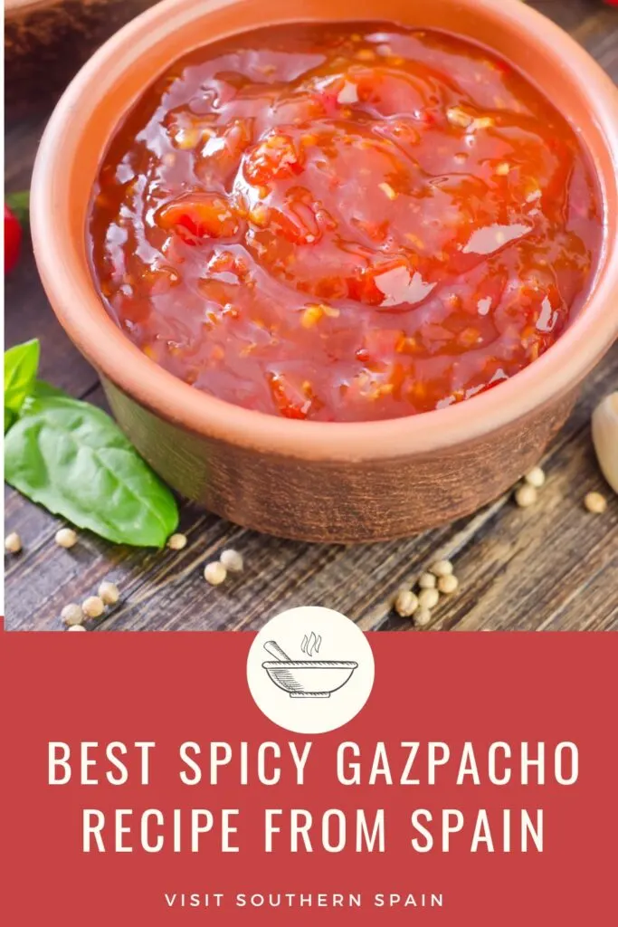 a pin with a clay bowl of spicy gazpacho on a wooden table.