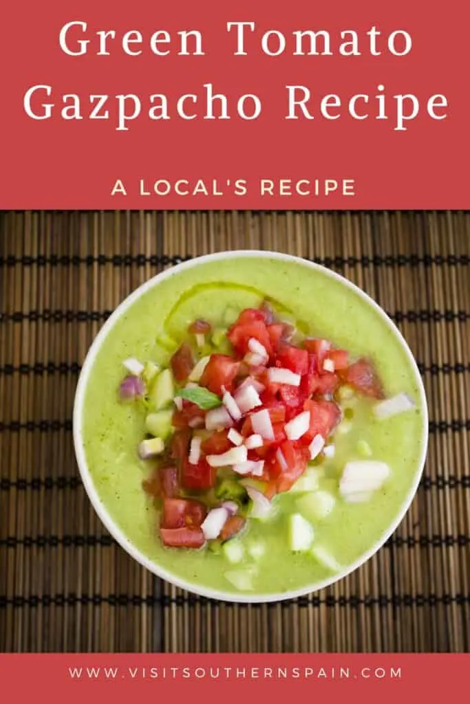 a pin with a bowl of green tomato gazpacho decorated with fresh vegetables.