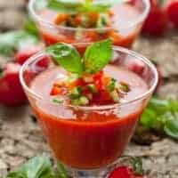 2 cups of gazpacho shot decorated with fresh basil.