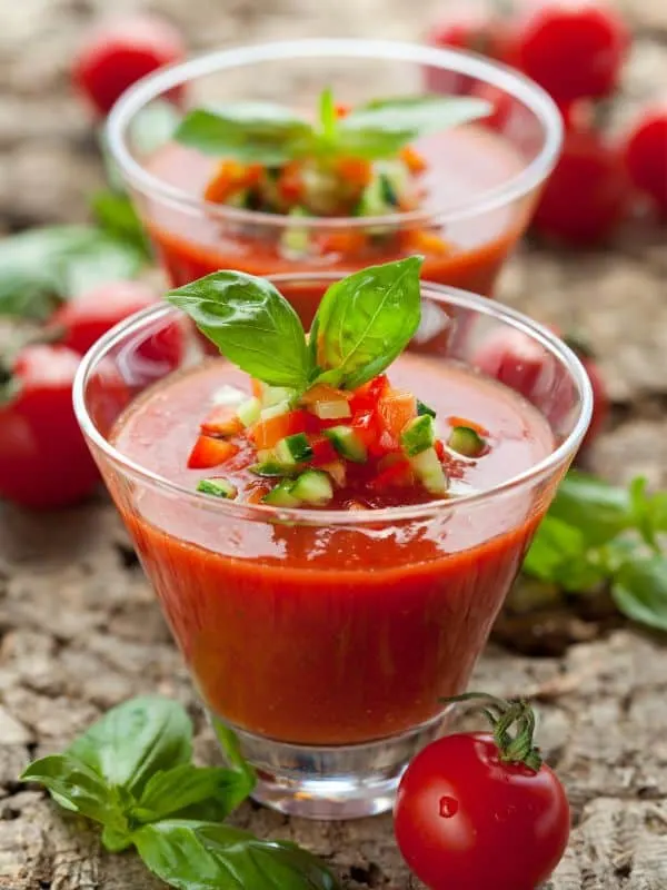 2 cups of tomato basil gazpacho decorated with fresh basil.