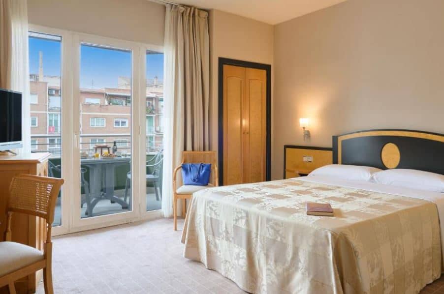 bedroom with TV, desk and balcony at Hotel Macia Condor, Granada