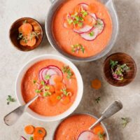Spanish pumpkin carrot soup served in 3 bowls decorated with carrot slices