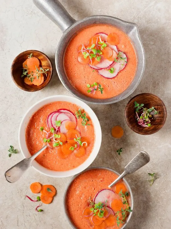 carrot gazpacho served in 3 bowls decorated with carrot slices