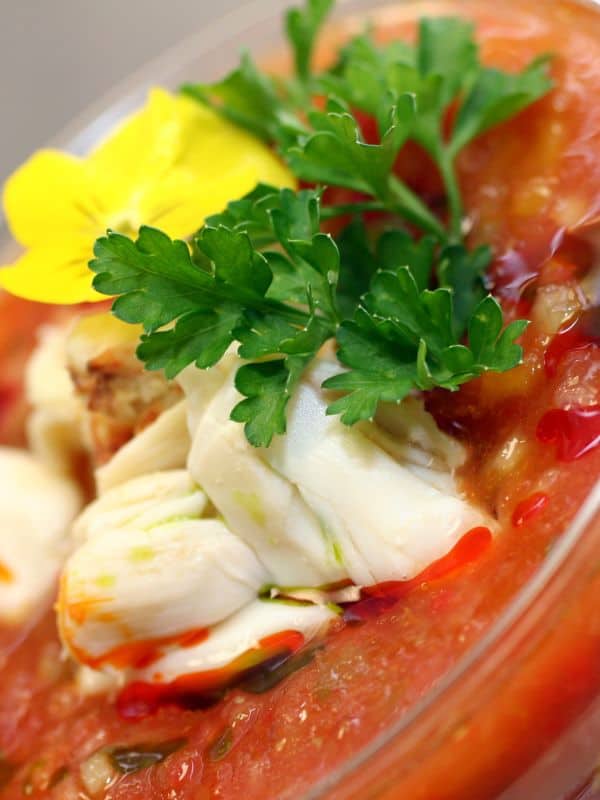 closeup of a crab gazpacho in a glass bowl.