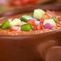 closeup with cold vegetable soup in a clay pot decorated with fresh vegetables