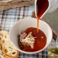 cold shrimp soup in a bowl served with 2 slices of bread on a rustic table