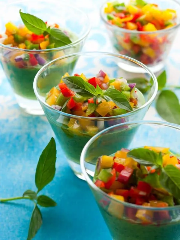 Green Tomato Avocado Gazpacho in glass bowls with fresh vegetables on top