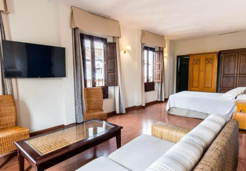 interior of a room with bed, sofa and TV at Hotel Plaza Nueva, Granada