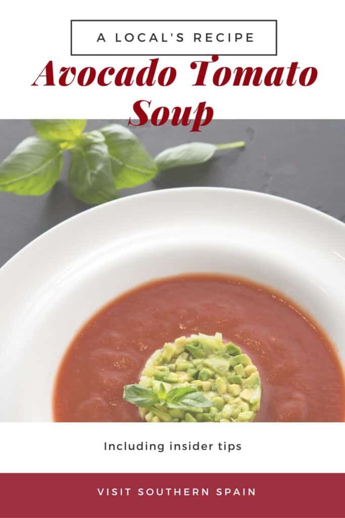 a pin with a cold avocado tomato soup decorated with chopped avocado.