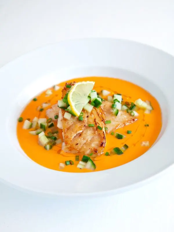 a bowl of bacalao gazpacho decorated with fresh cucumber