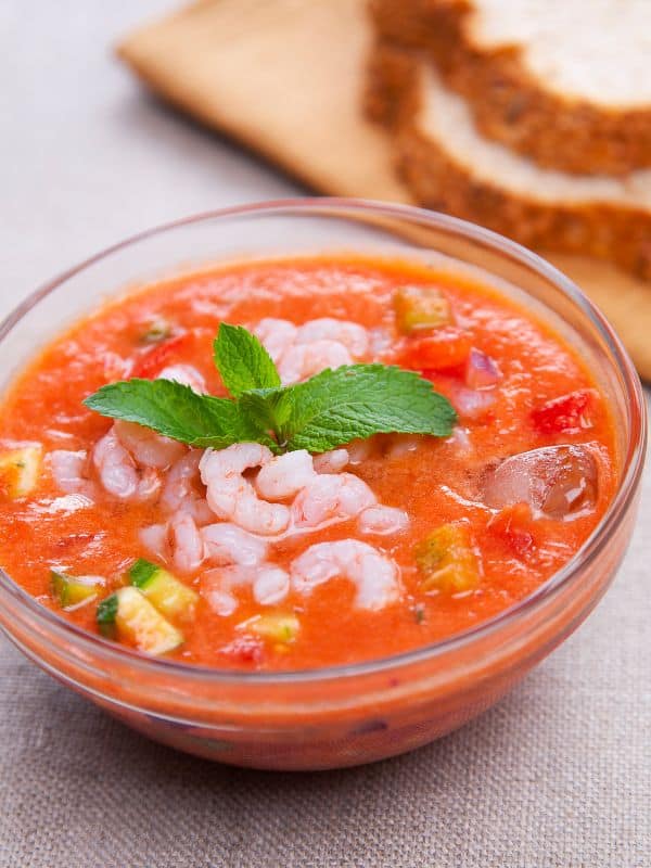a glass bowl with seafood gazpacho served with slices of bread - Best Spanish Seafood Gazpacho Recipe