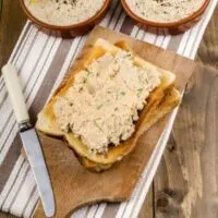 2 bowls of fresh mackerel pate recipe next to a toast with pate on a wooden board.