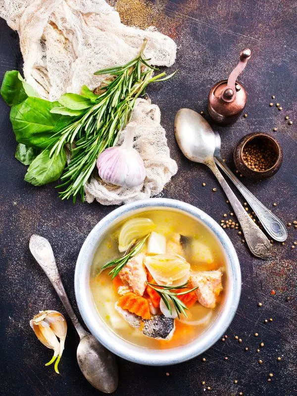 a bowl of mackerel soup recipe on a black surface with other ingredients next to it. - Comforting Mackerel Soup Recipe from Spain