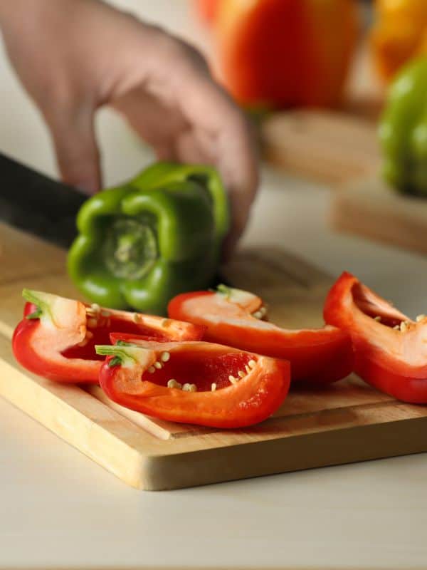 green and red peppers being cut on a board for the healthy mackerel recipe