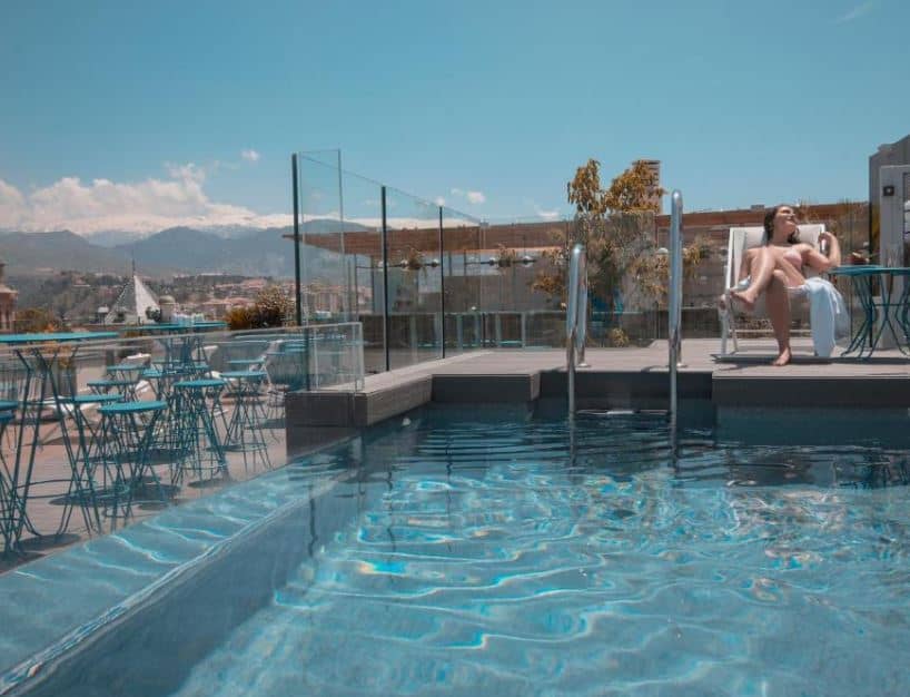woman sunbathing by a panoramic rooftoop pool at Barcelo Carmen Granada, best 4 star hotels in Granada